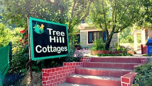 A sign for Tree Hill Cottages with a brick pathway leading to the entrance. - Gezellig Inn - Kanyal Villas (Manali)