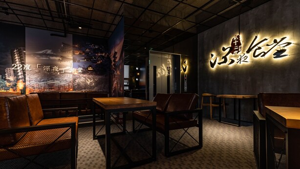 Un interior moderno con asientos, una pared con texto iluminado y vistas a la ciudad.
