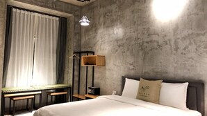 Habitación de hotel moderna con una cama grande, un escritorio con silla, una mesita pequeña y una radio.