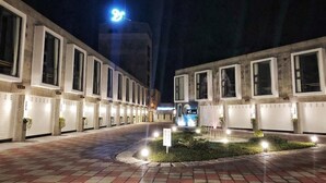 Un pasillo de hotel con habitaciones similares, una fuente en el centro y un letrero bien iluminado.