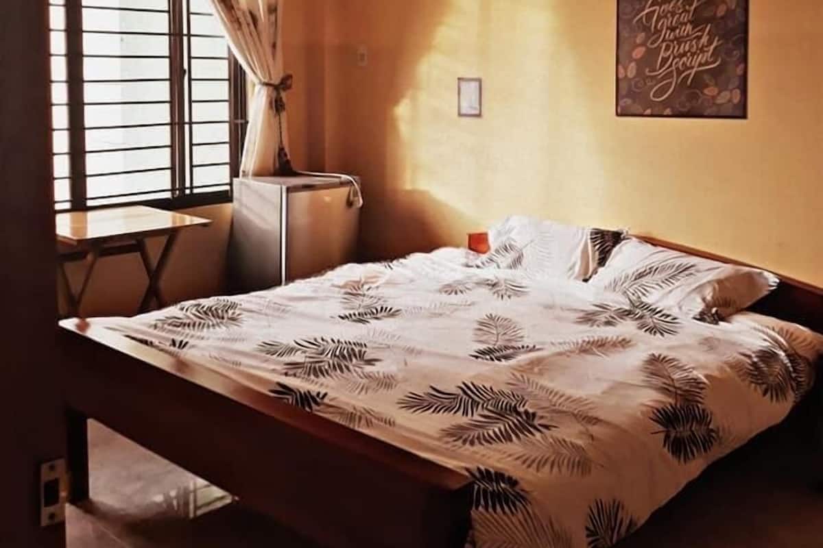 Une chambre à coucher avec un lit, un bureau et une fenêtre avec des rideaux.