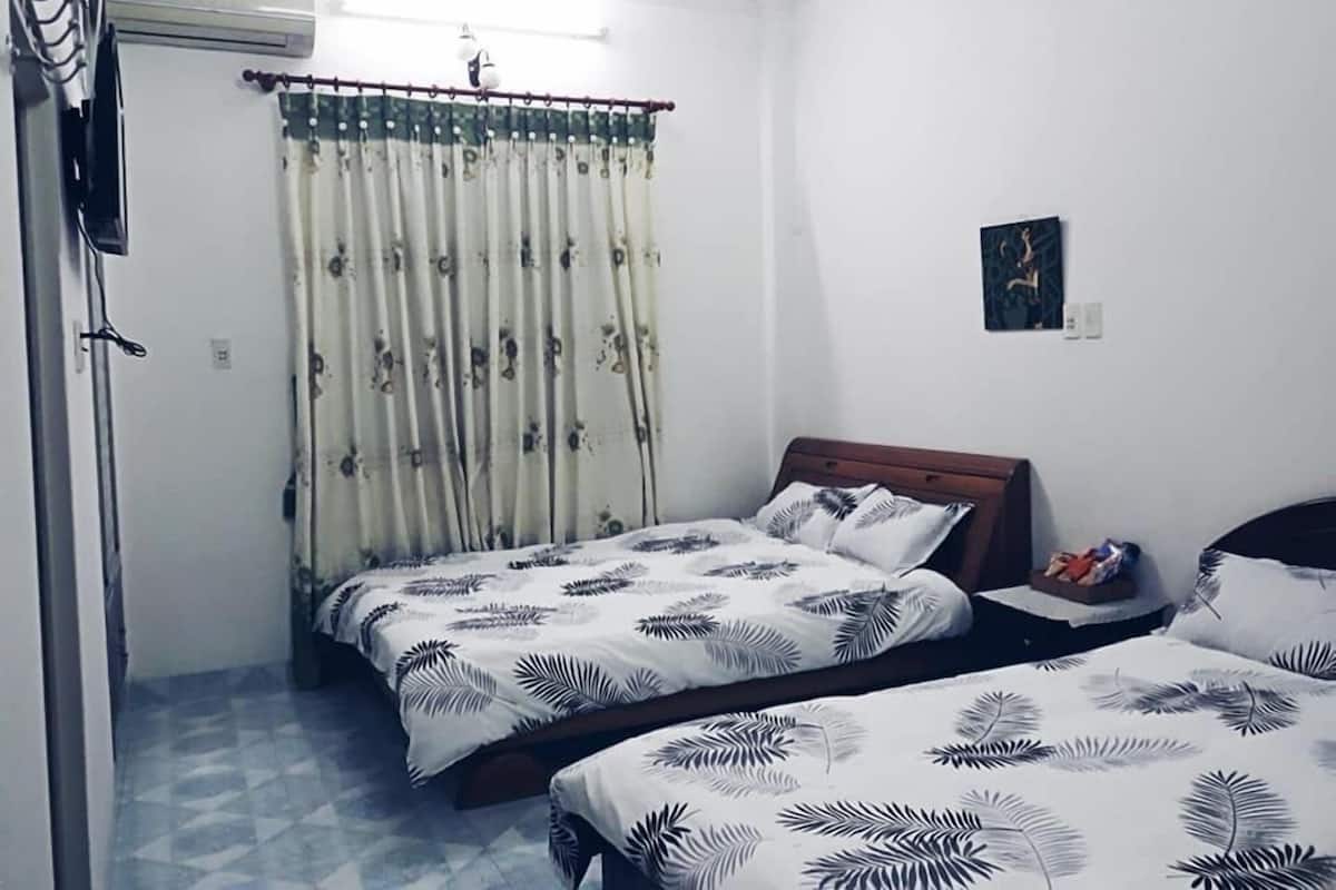 Une petite pièce propre, avec un lit, une table de chevet et un rideau.