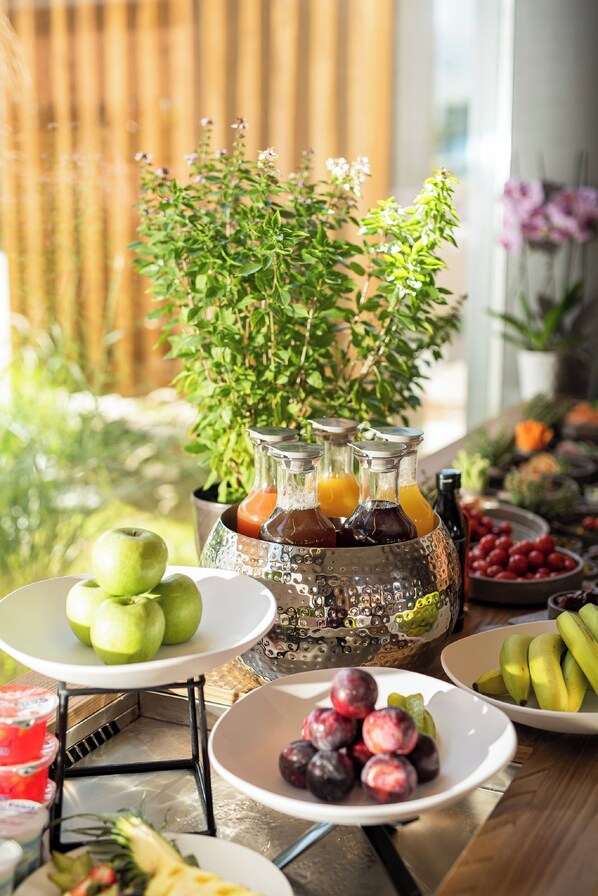 A table with various fruits, a potted plant, and bottles of beverages. - Pilot Amphora Boutique Hotel - Adults Only (Apokoronas)
