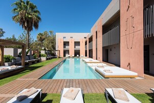 Una piscina al aire libre, sombrillas, sillones reclinables de piscina