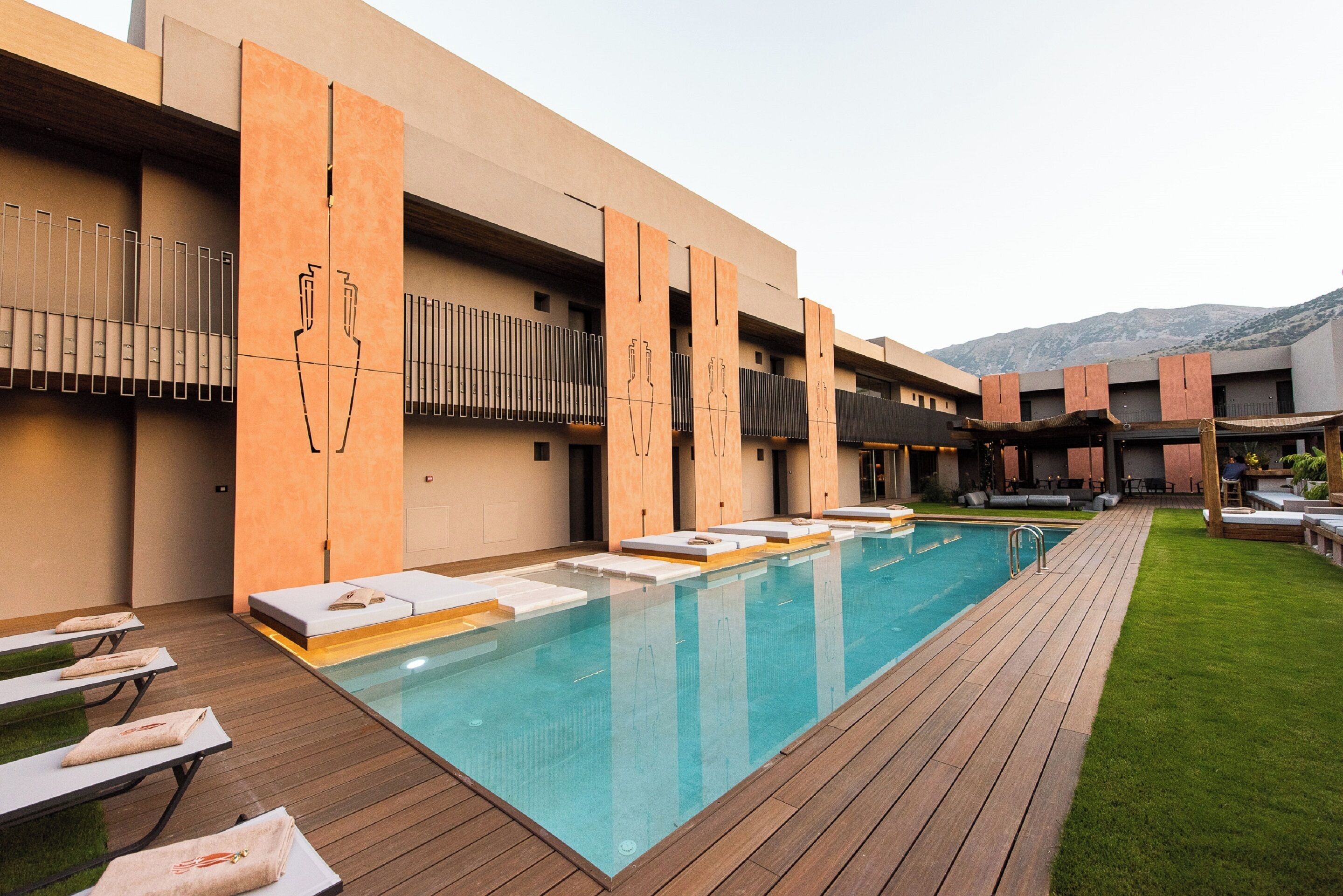 Ein modernes Hotel mit Schwimmbad, Holzdeck und Sitzgelegenheiten im Freien.