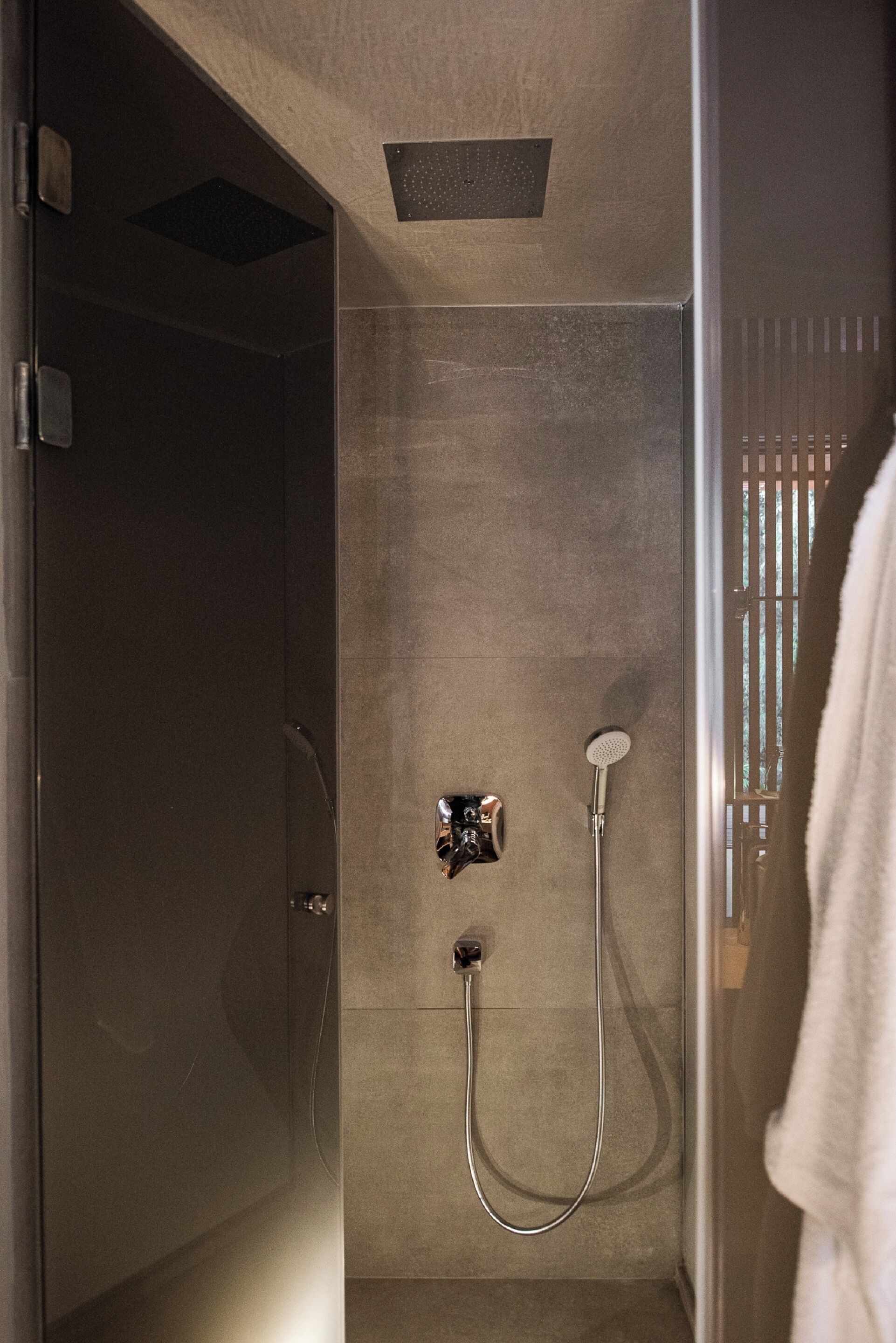 A modern shower with a handheld showerhead and a wall-mounted faucet.