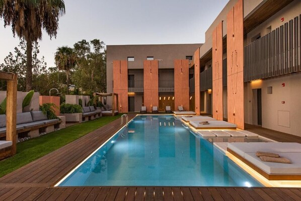 A modern pool area with a rectangular pool, lounge chairs, and a wooden deck. - Pilot Amphora Boutique Hotel - Adults Only (Apokoronas)