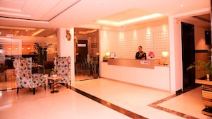 A hotel reception area with a receptionist desk, seating area, and a glass door entrance. - The Vegas By De Pavilion, Delhi Airport (New Delhi)