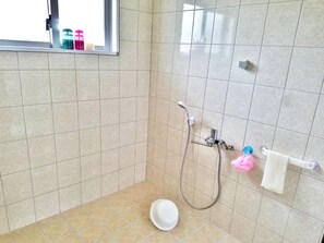 A bathroom with a shower, a toilet, and a window.
