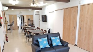 A modern living room with a black leather sofa, a glass coffee table, and wooden doors. - Resort Inn Gabusoka (Nago)