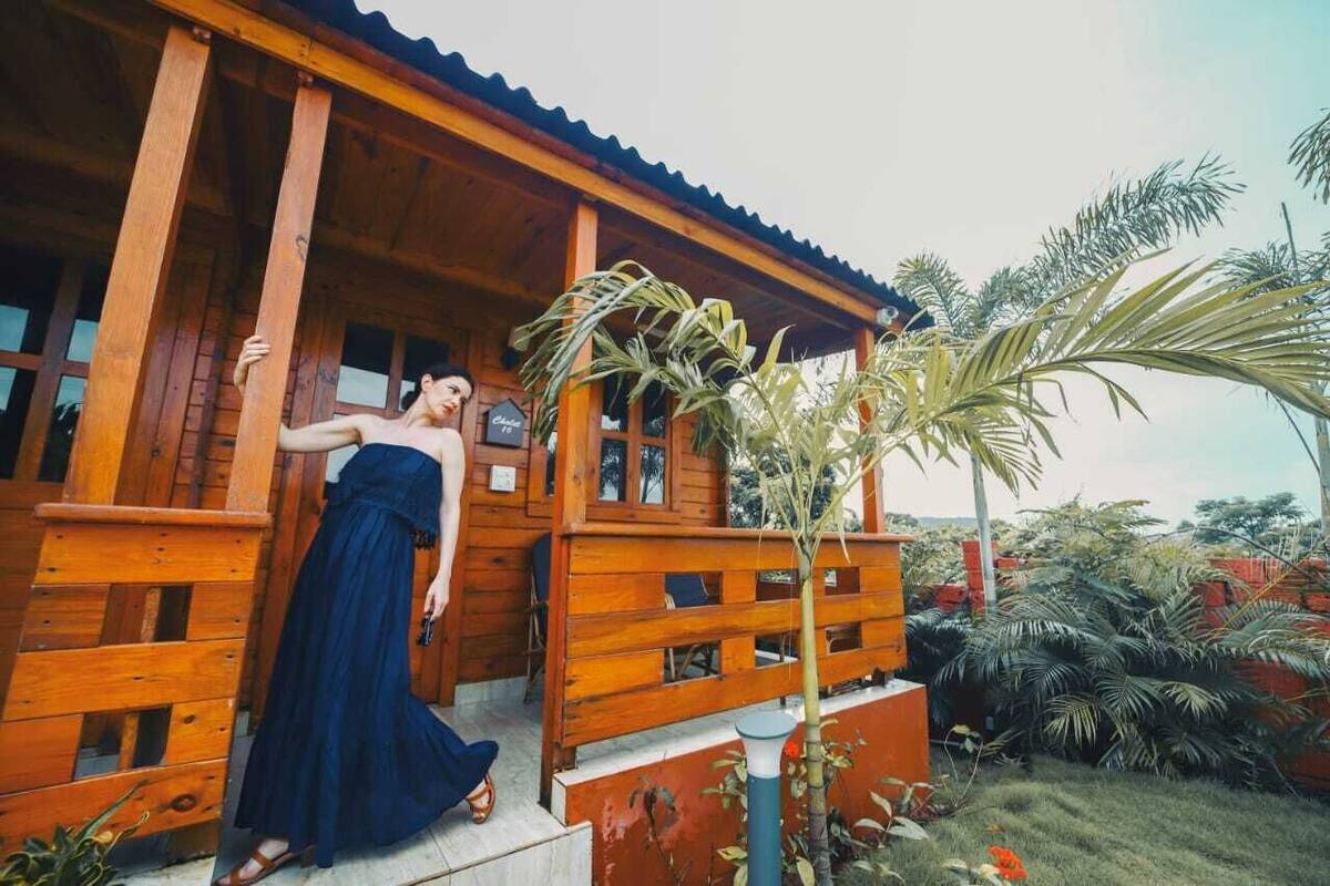 A wooden building with a porch, a sign that reads "Chalet," and a small tree in the foreground.