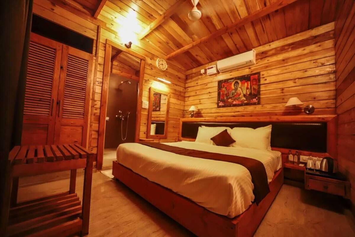 A wooden cabin bedroom with a bed, a nightstand, a wall clock, and a painting.