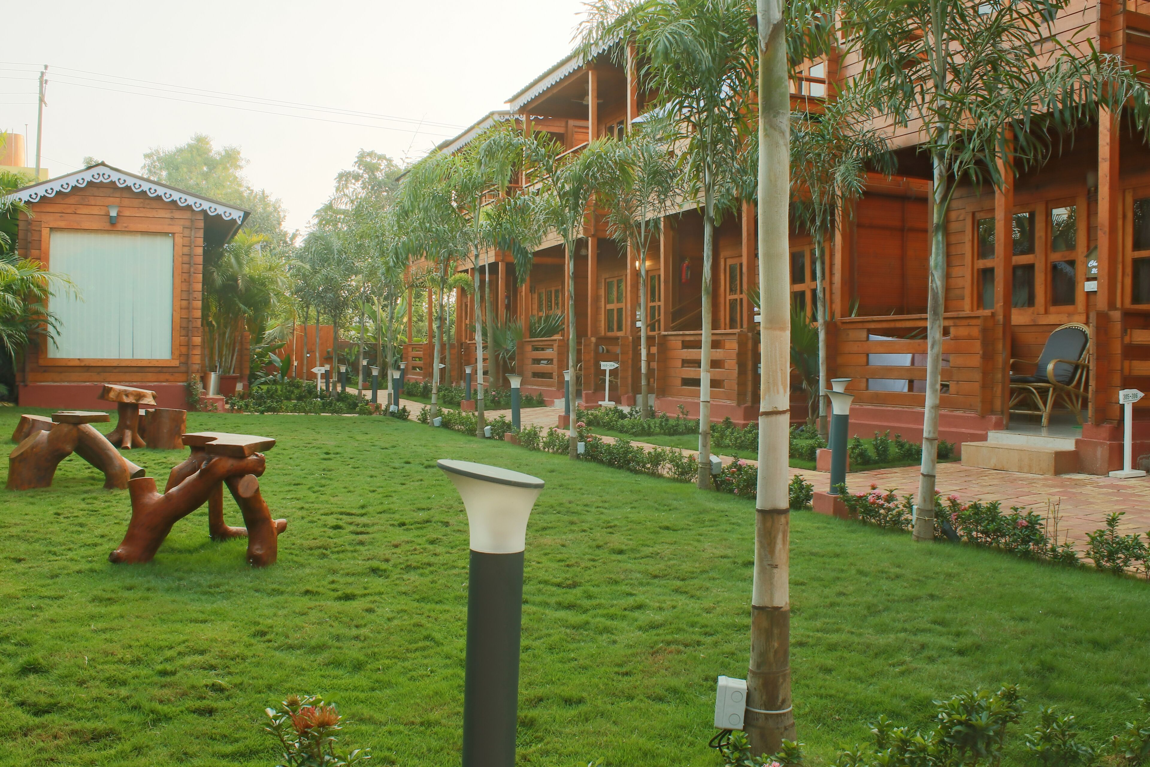 A wooden building with multiple balconies and a well-maintained garden with grass and trees.