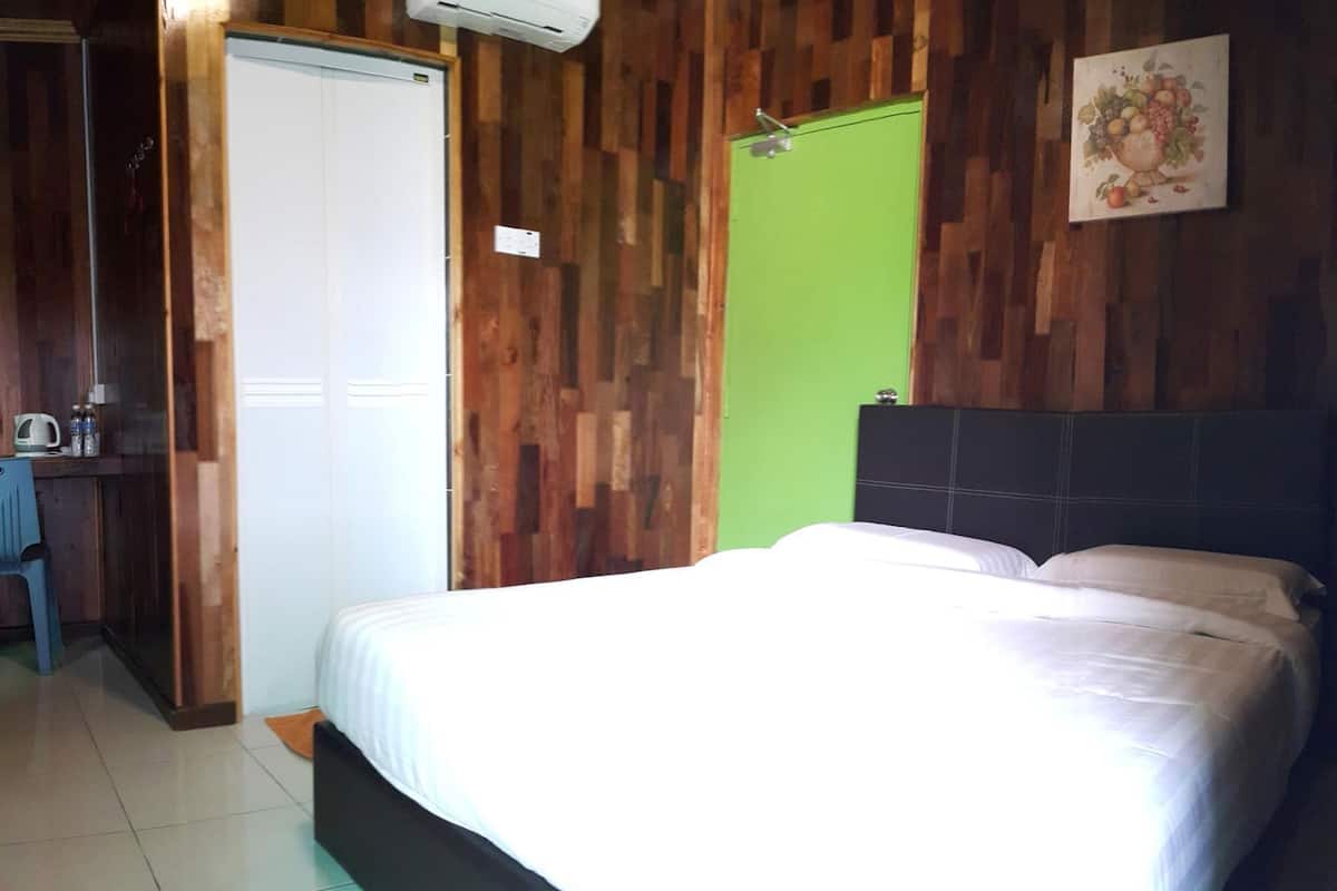 A bedroom with a bed, a green door, and a wall-mounted air conditioner.