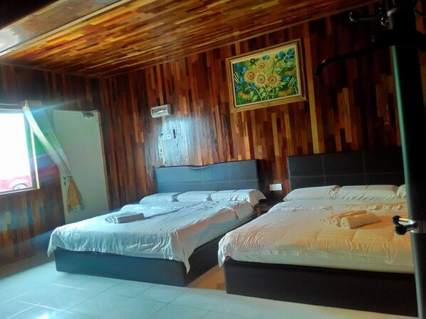 Una habitación con dos camas, paredes de madera, un cuadro y una ventana.