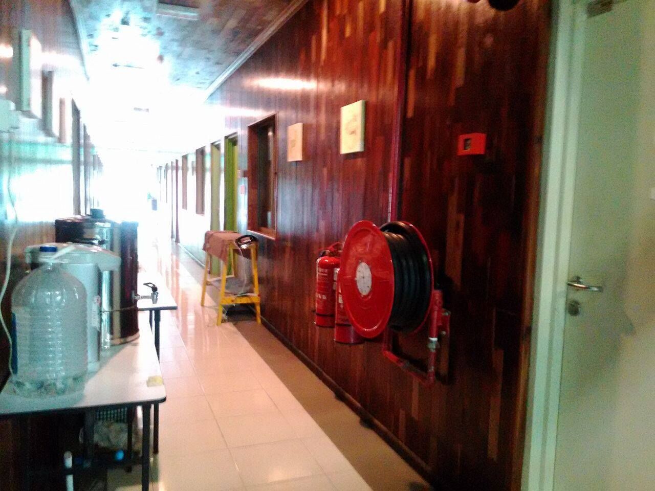 A hallway with wooden walls, a fire hose reel, and a water dispenser.