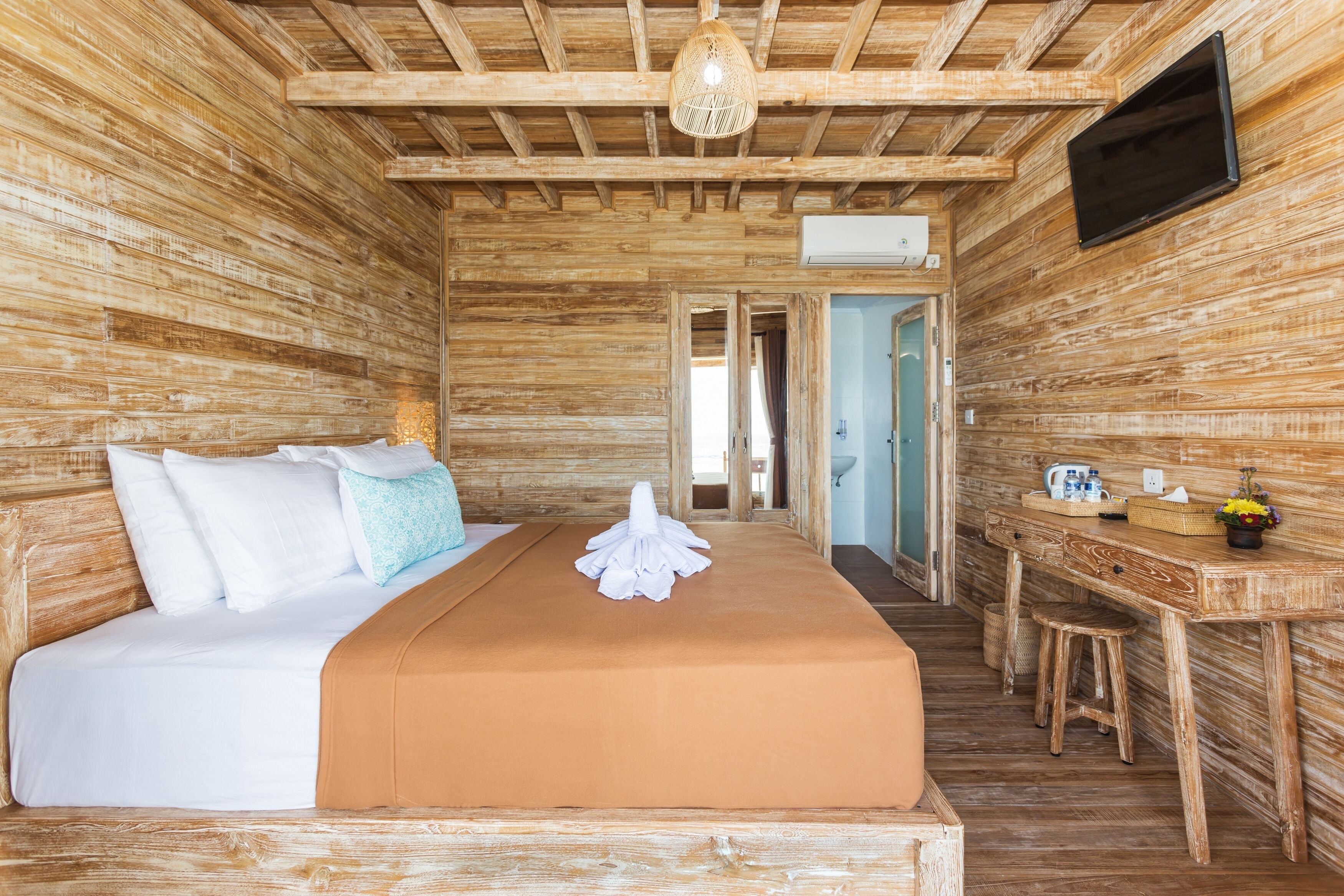 A wooden room with a bed, a desk, and a television.