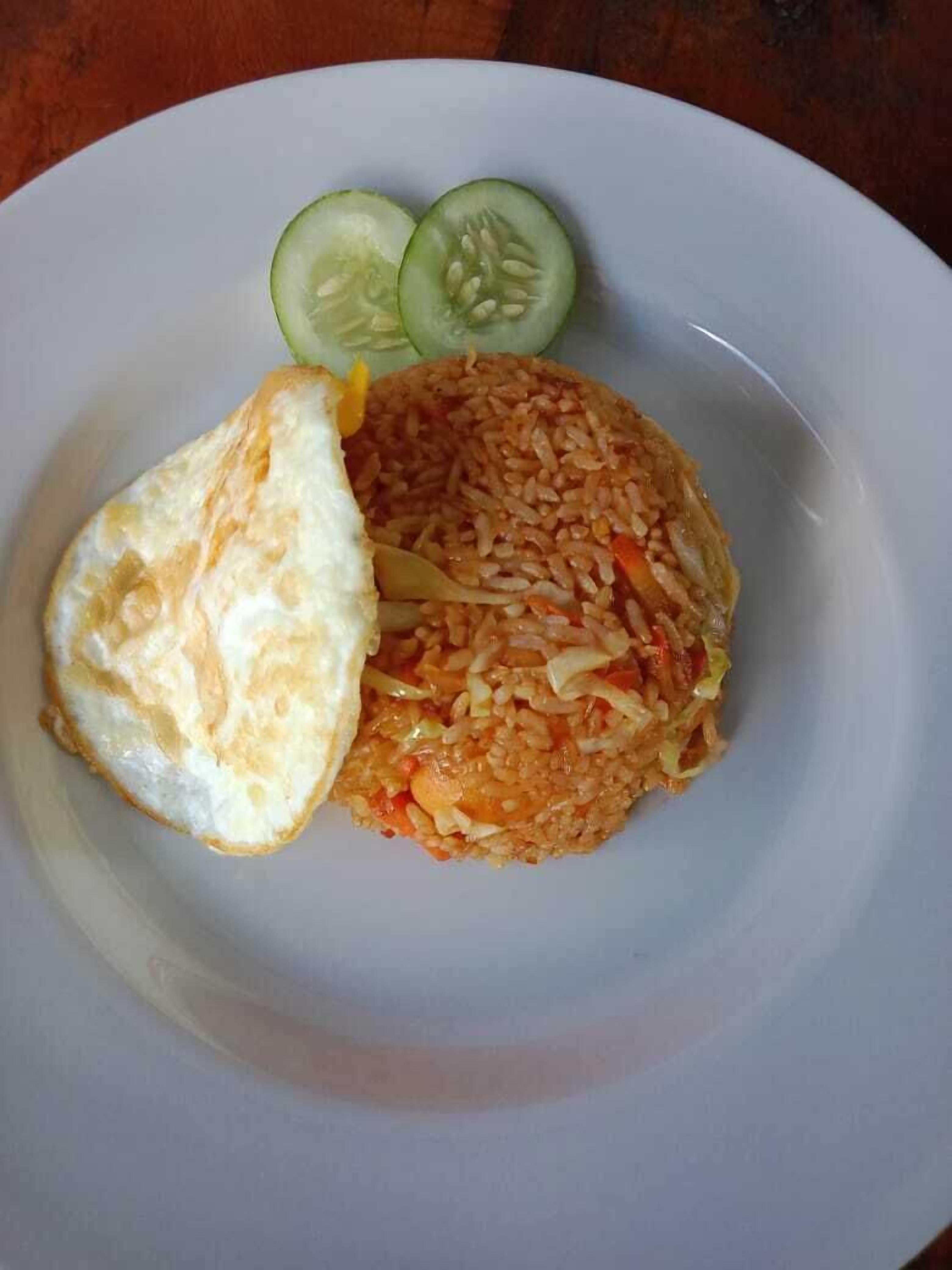 Egy tányér rántott rizzsel, egy rántotta és két szelet uborka.