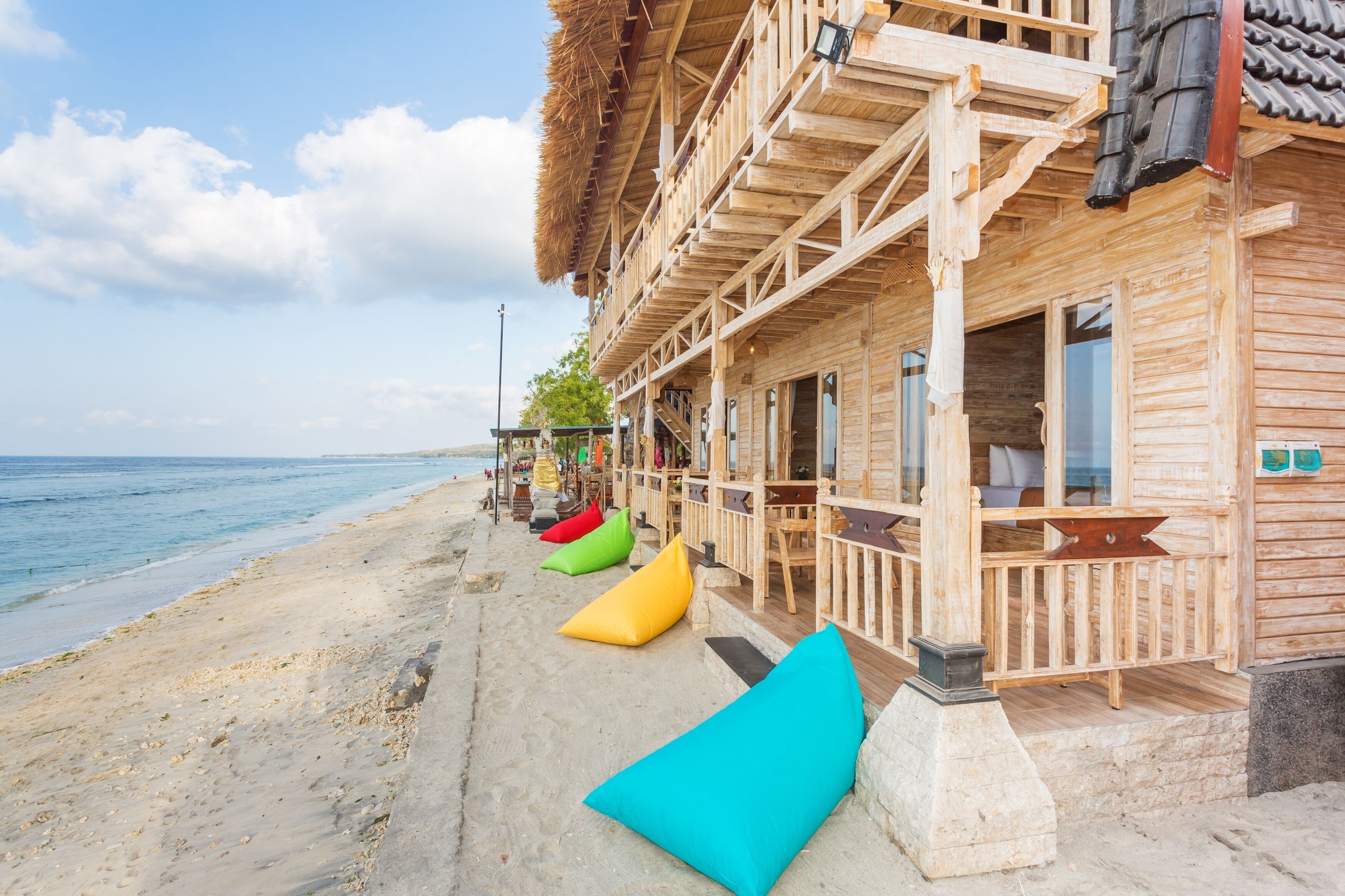 A wooden beachside building with a balcony, a sandy beach, and a view of the sea.