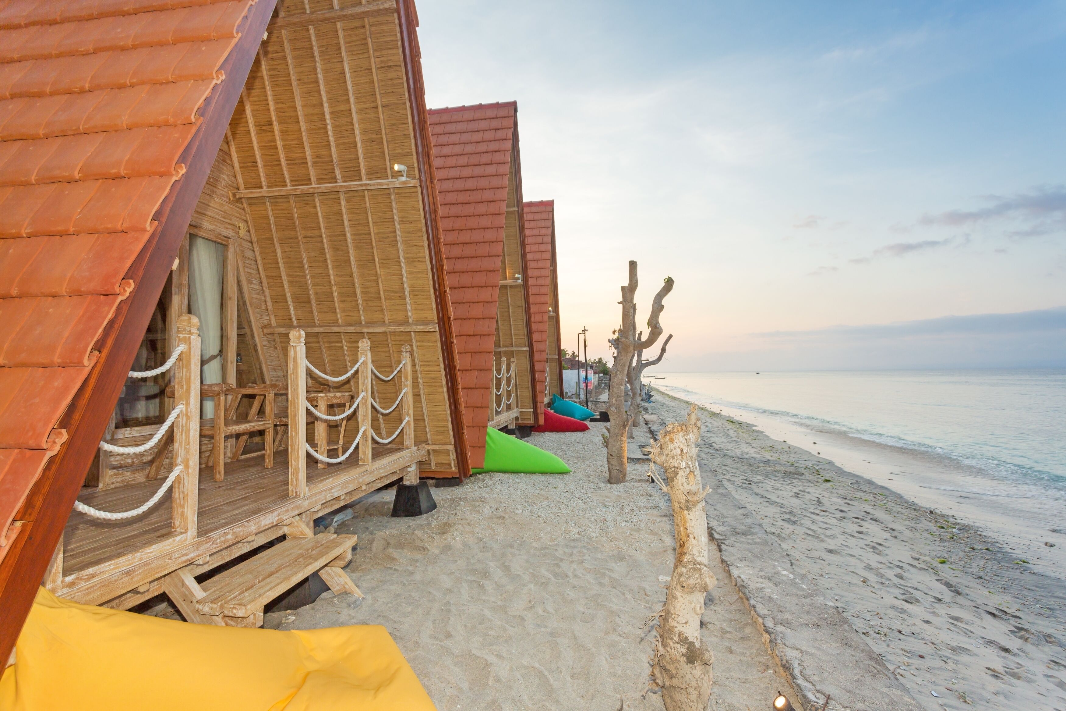 A row of wooden beach huts with a sandy beach and ocean in the background.