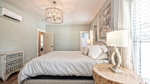 Quarto com cama, mesa de cabeceira, luminária e obra de arte na parede.