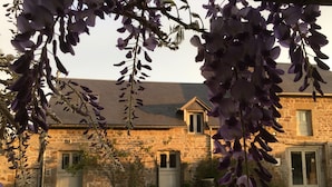 A stone building with a gravel driveway and a garden.