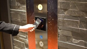 Une main insérant une carte dans le lecteur de cartes d’un ascenseur.