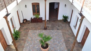 A courtyard with a patterned floor, potted plants, and a central column.