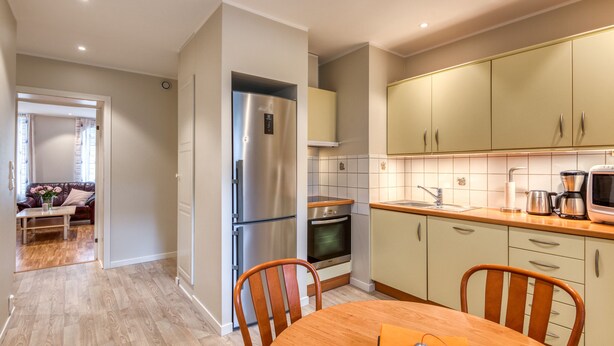 A modern kitchen with stainless steel appliances, wooden chairs, and a dining table. - Trondheim Leilighetshotell (Trondheim)