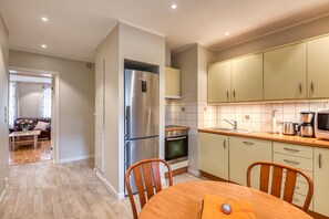 Una cocina moderna con electrodomésticos de acero inoxidable, sillas de madera y una mesa de comedor.
