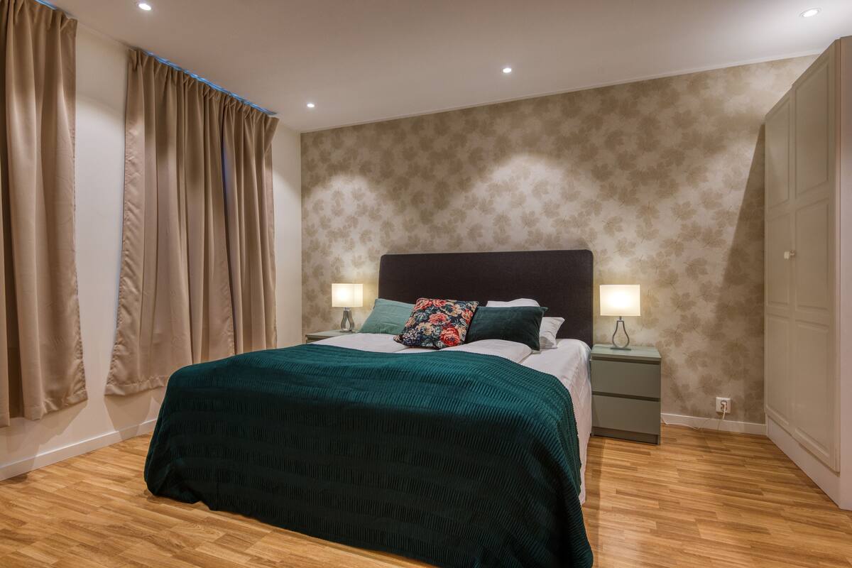 A neatly arranged bedroom with a bed, nightstands, and a patterned wall.