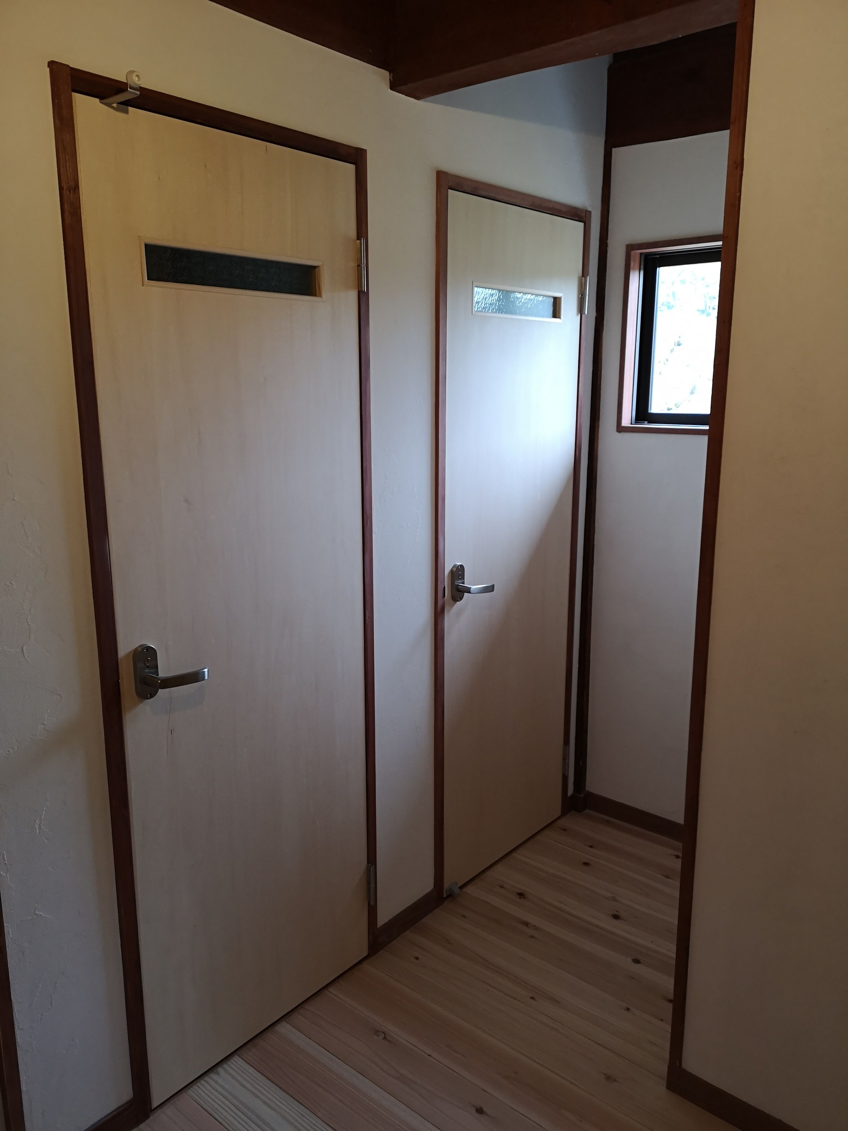 A hallway with wooden doors and a small window.