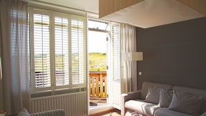 Ein Wohnzimmer mit einer Couch, einem gestreiften Sessel, einem Holztisch und einem Glastisch mit einer Dekoration.