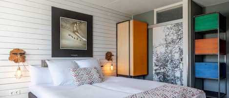 Ein modernes Schlafzimmer mit einem großen Bett, einem gerahmten Bild an der Wand und einem Kleiderschrank mit vielen Fächern.