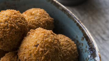 Un tazón de bolitas rebozadas con salsa aparte.