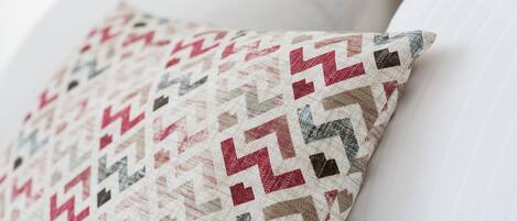 A close-up of a patterned pillow on a white sofa.