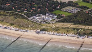 Luftaufnahme eines Küstenresorts mit Strand, Parkplatz und einer Reihe von Strandhäusern.