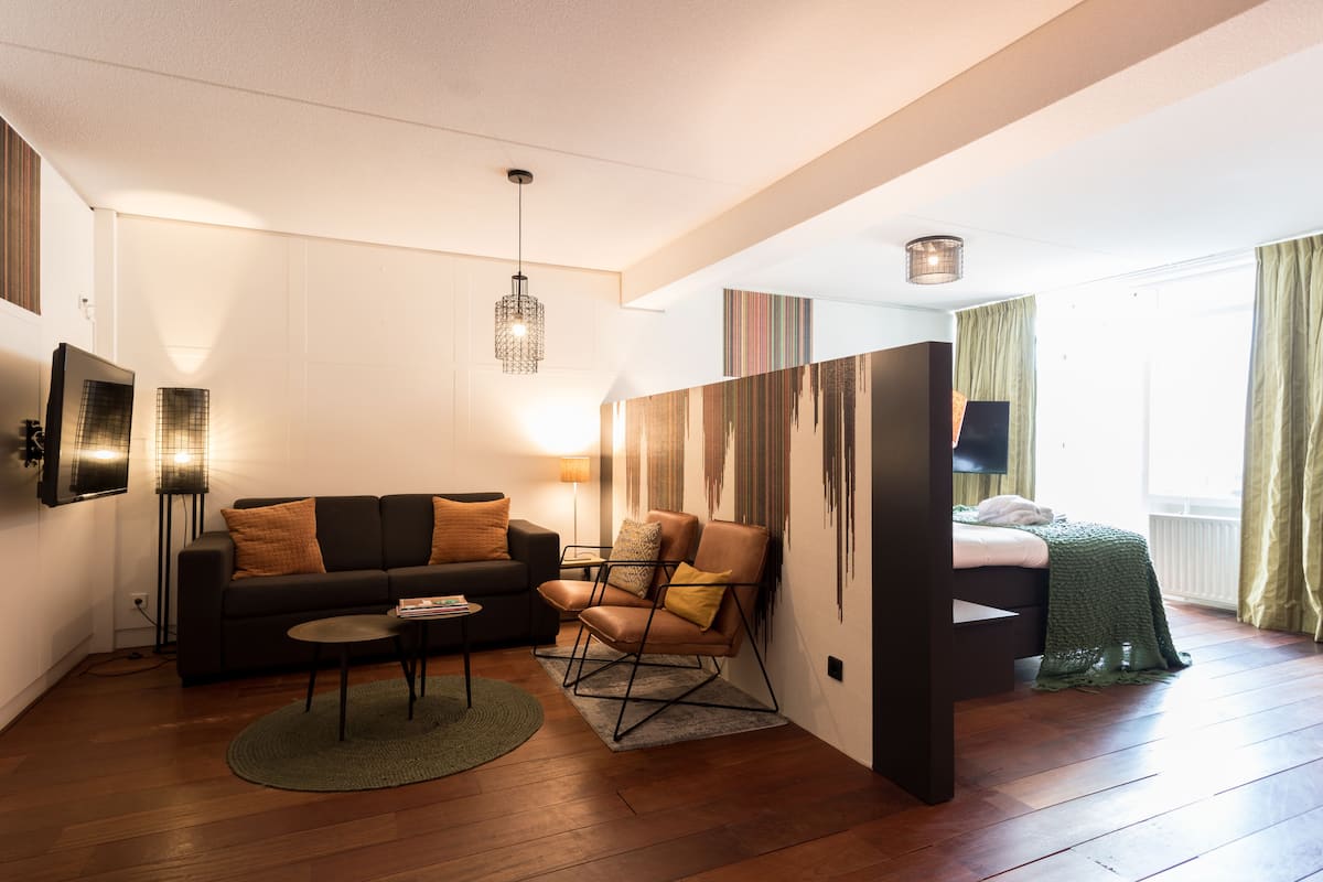 A modern hotel room with a sofa, armchair, and a bed.