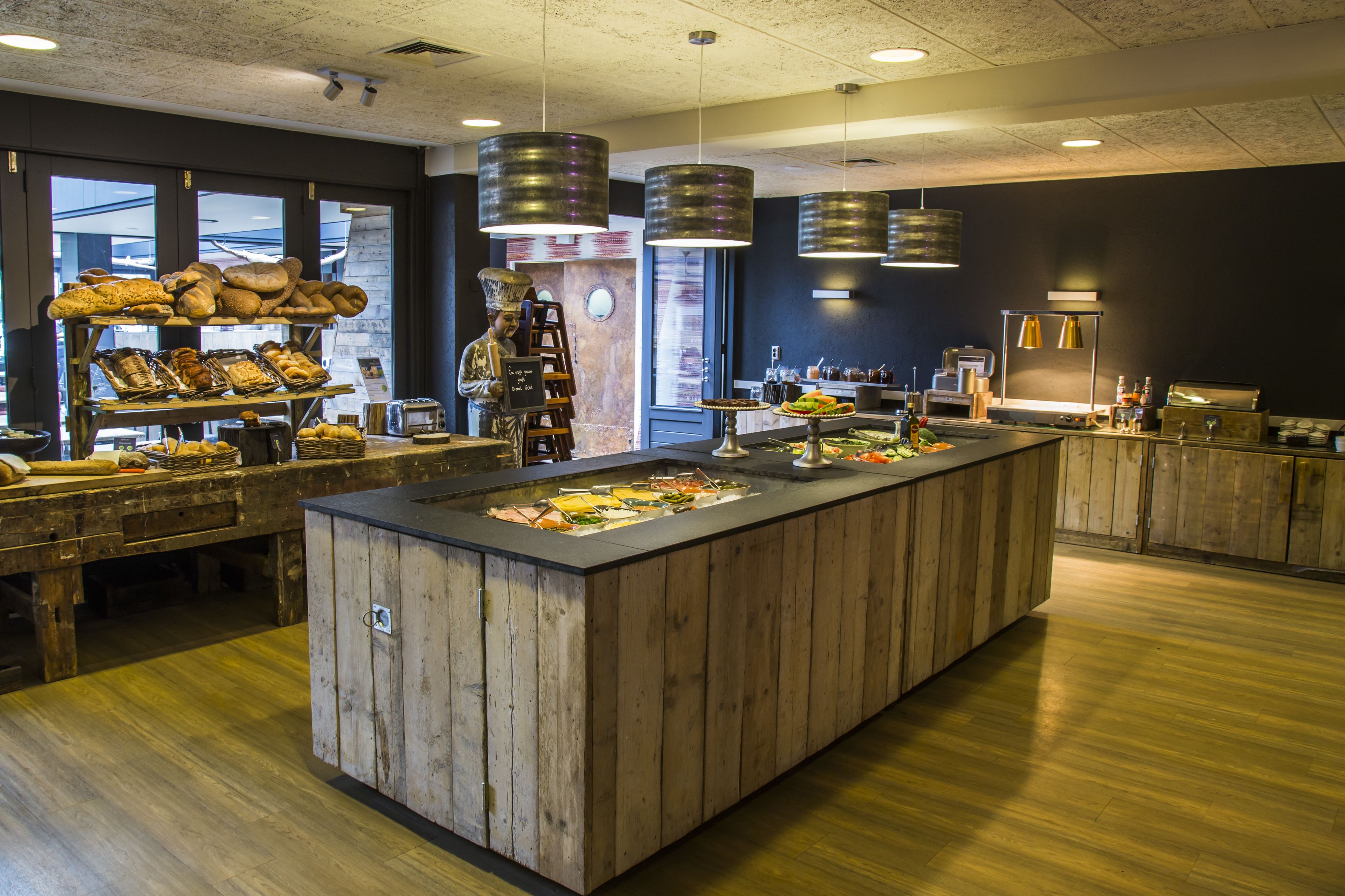 Angolo buffet con banconi in legno, diversi cibi e lampade a sospensione.