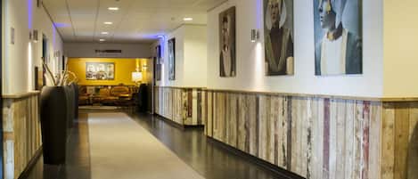 Un pasillo de hotel con paneles de madera, una recepción y obras de arte en las paredes.