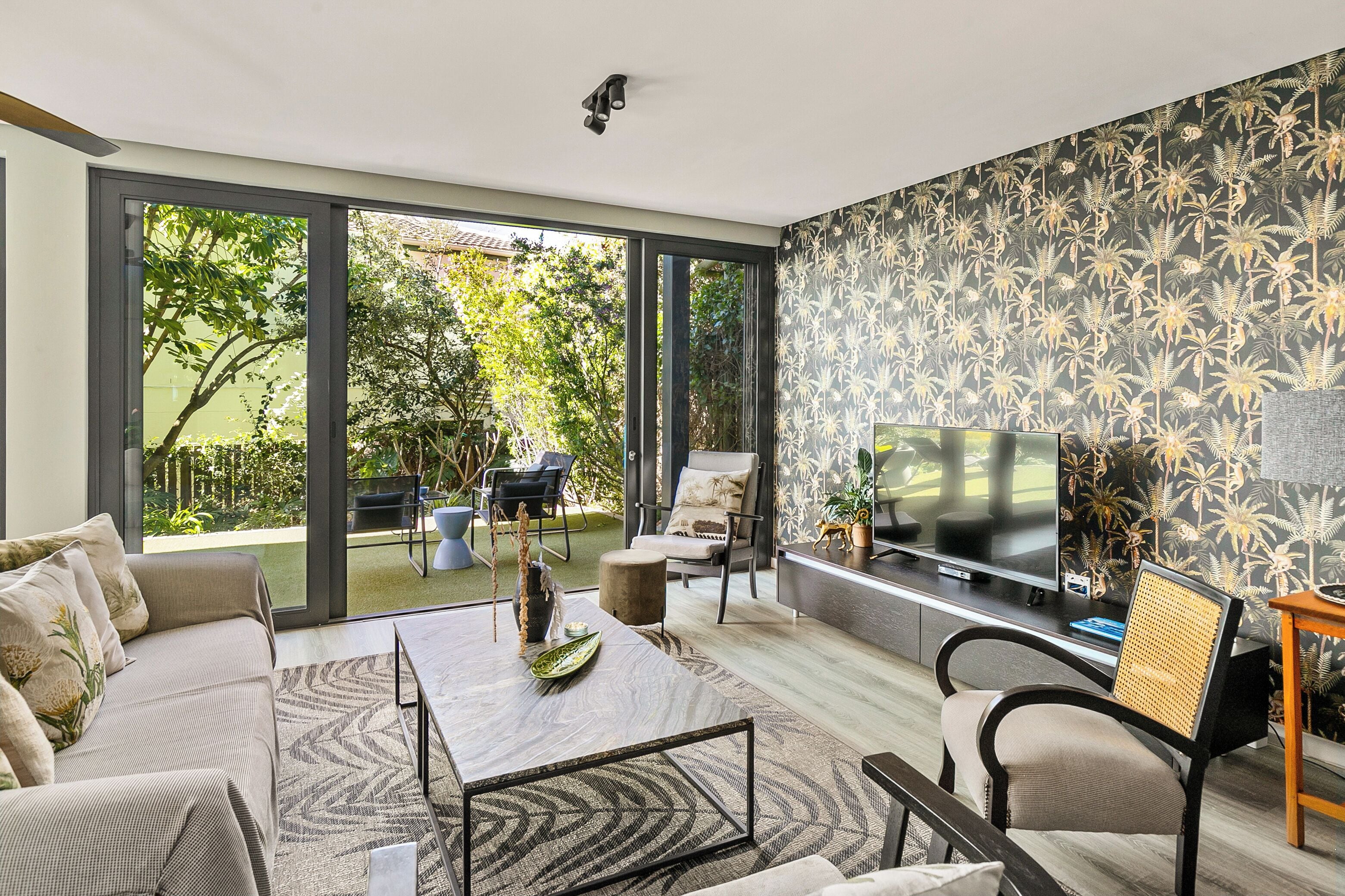 Una sala moderna con un televisor grande, asientos cómodos y vistas al exterior.