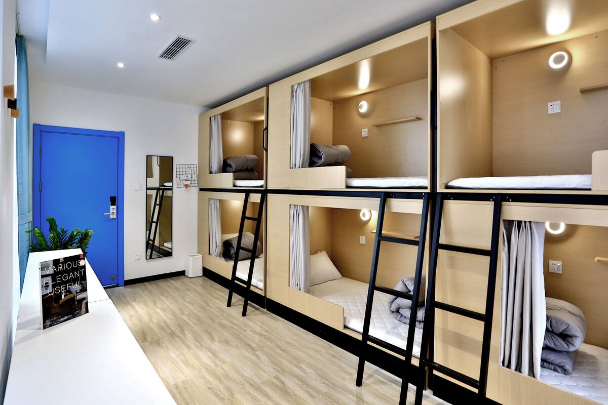 Una habitación de hotel moderna con literas, un escritorio y una puerta azul.