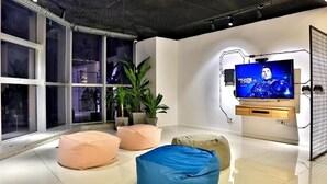 A modern living room with large windows, a flat-screen TV, and several bean bags. - Hangzhou Infinity Youth Hostel (Hangzhou)