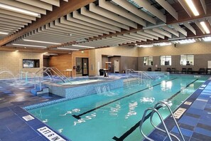 Una piscina interior con marcas de carril definidas, un vestuario y una estructura de techo de madera.