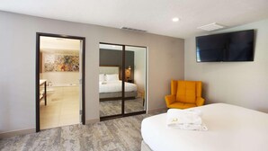 Une chambre d’hôtel équipée d’un lit, d’une chaise, d’une télévision et d’une salle de bain visible à travers une porte coulissante.