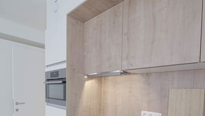A modern kitchen with white cabinetry, a wooden countertop, and built-in appliances. - Florence en Ville (Brussels)