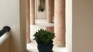 A corridor with columns, a potted plant, and a view into another room. - Ariadne Apartments (Zakynthos)