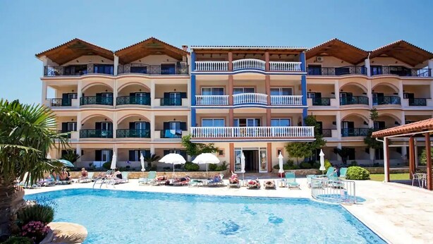 A hotel with a swimming pool, multiple balconies, and sun loungers. - Ariadne Apartments (Zakynthos)