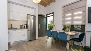 Uma cozinha moderna com armários brancos, uma geladeira de aço inoxidável e um espaço de jantar com cadeiras azuis e uma mesa de madeira.