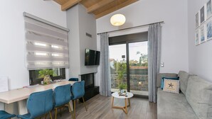 Uma sala de estar moderna com sofá, mesa de jantar com cadeiras, lareira e uma janela grande com cortinas.